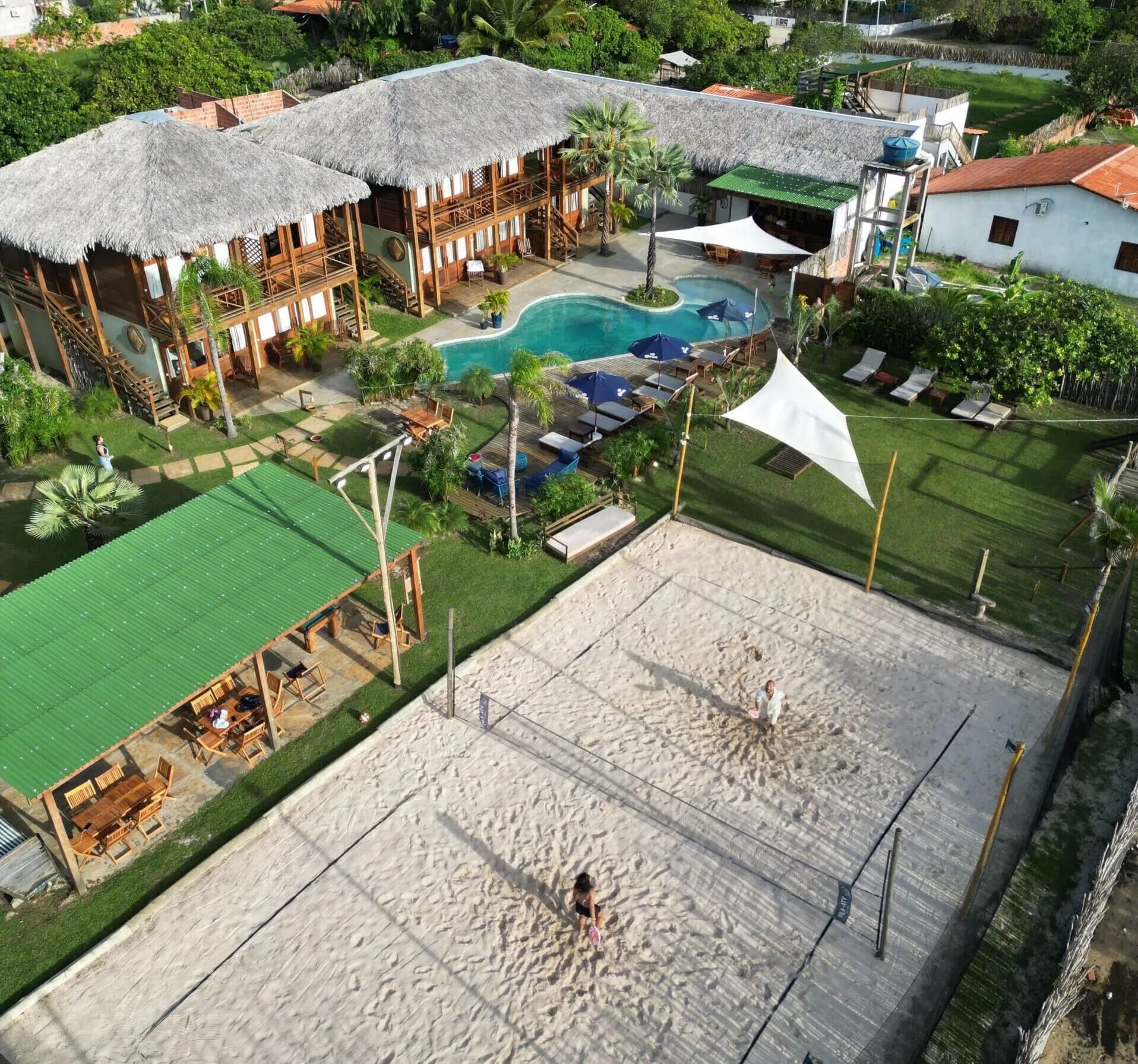 Vista aérea da Vila Aty com piscina, quadra de areia e chalés